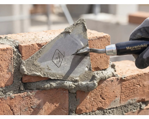 Maurerkelle beim Mauern von Ziegelsteinen mit Mörtel