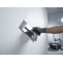 Main avec une lisseuse à plâtre en train de lisser un mur