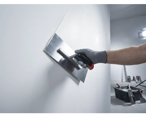 Main avec une lisseuse à plâtre en train de lisser un mur