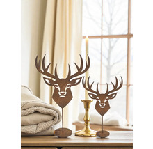 Dekorative Hirschfiguren aus Metall auf einem Tisch, neben einer Kerze und einer gefalteten Decke