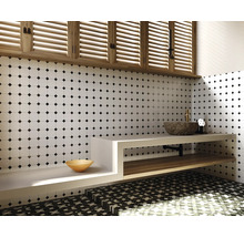 Badezimmer mit weißer Fliesenwand mit schwarzem Punktmuster, Waschtisch mit Steinwaschbecken und Holzregal