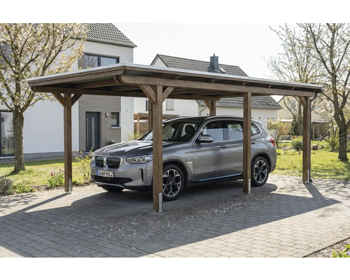 Une voiture est garée sous un carport en bois à l'extérieur.