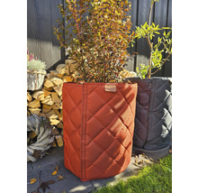 Deux bacs à plantes avec motif matelassé et plantes devant, pile de bois et décoration