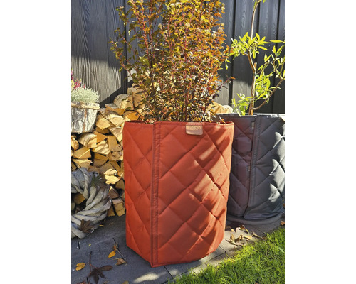 Deux bacs à plantes avec motif matelassé et plantes devant, pile de bois et décoration
