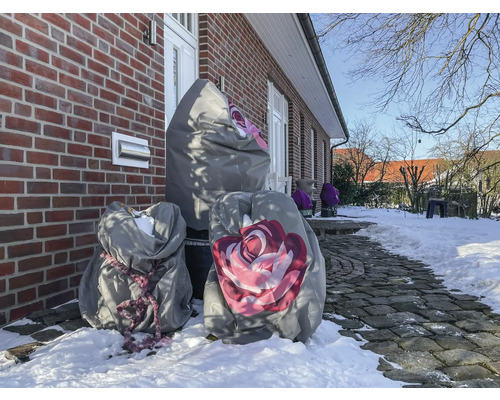 Paysage hivernal avec des plantes sous des housses de protection devant une maison en briques