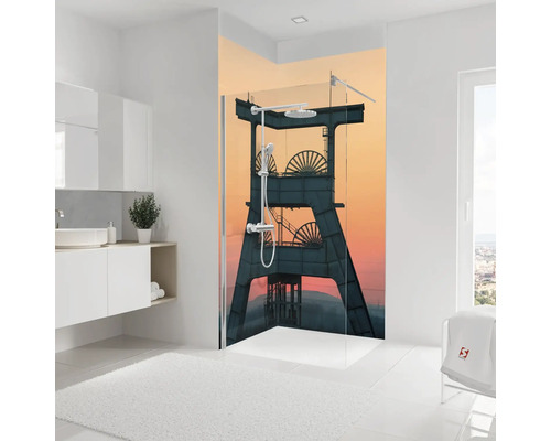 Paroi de douche avec motif industriel d'un chevalement devant un ciel de soirée dans une salle de bains lumineuse.