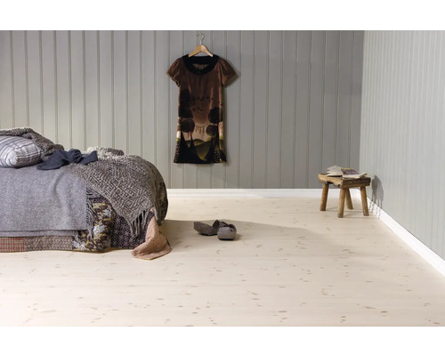 Chambre avec sol clair aspect bois, revêtement mural en panneaux de bois gris, lit avec couvertures et tabouret en bois rustique.