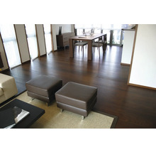 Parquet sombre dans un salon moderne avec coin repas, table en bois et poufs.