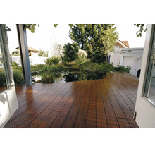 Terrasse en bois faite de planches rainurées avec vue sur un bassin de jardin avec des nénuphars et une végétation luxuriante.