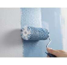 Une personne peint un mur avec un rouleau à peinture.