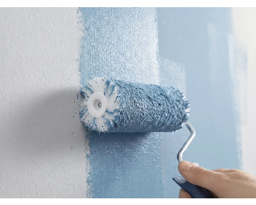 Une personne peint un mur avec un rouleau à peinture.