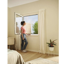 Femme à la fenêtre ouverte avec moustiquaire dans la chambre