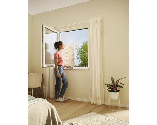 Femme à la fenêtre ouverte avec moustiquaire dans la chambre