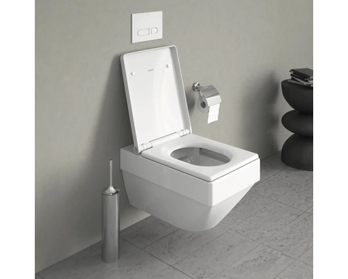 WC suspendu avec bride ouverte, plaque de commande, porte-papier toilette et brosse WC dans une salle de bains.