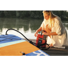 Frau pumpt ein Stand Up Paddle Board mit einer Einhell Luftpumpe auf einem Holzsteg auf