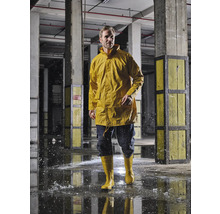 Homme en veste de pluie jaune et bottes en caoutchouc dans un environnement industriel