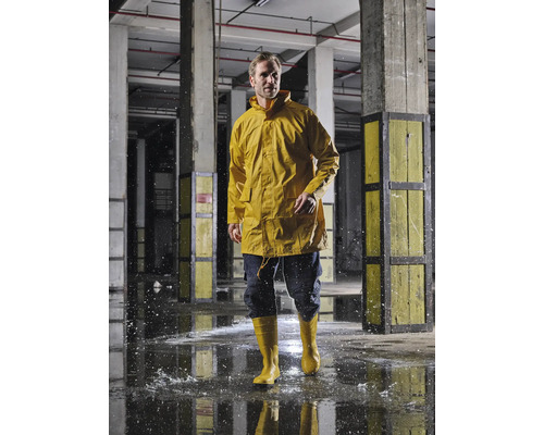 Homme en veste de pluie jaune et bottes en caoutchouc dans un environnement industriel