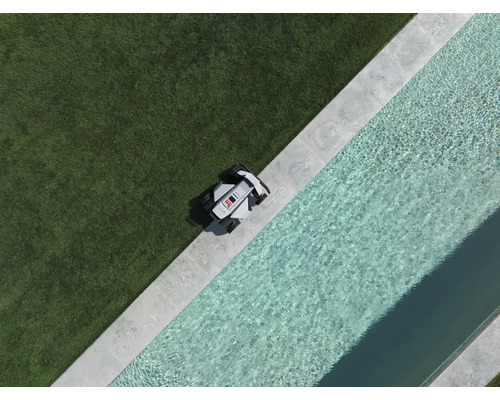 Mähroboter an der Kante einer Rasenfläche neben einem Pool mit Steineinfassung in der Draufsicht.