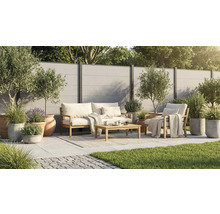 Salon de jardin moderne en bois sur une terrasse carrelée claire avec clôture, oliviers et graminées en pots.