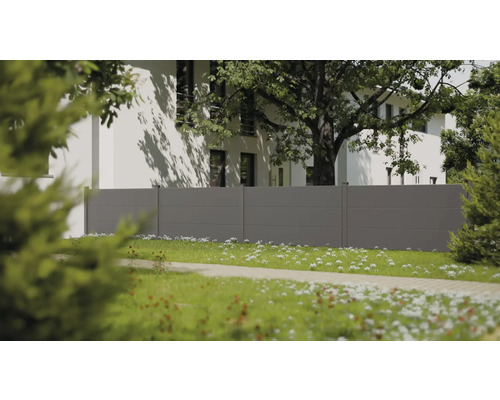 Clôture de jardin moderne grise à panneaux horizontaux dans un jardin lumineux avec une maison blanche et un grand arbre à l'arrière-plan.