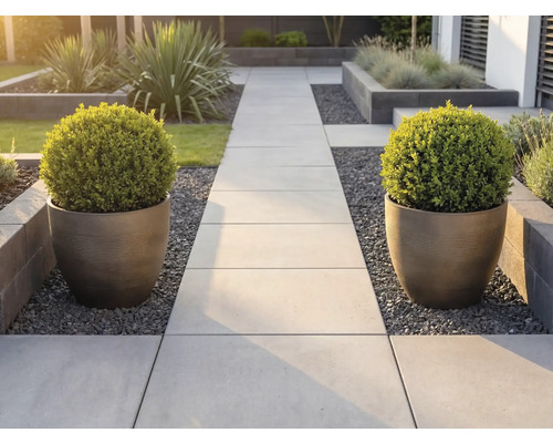 Allée de jardin moderne en dalles de pierre claire, bordée de deux grands bacs à fleurs striés contenant des buis taillés en boule.