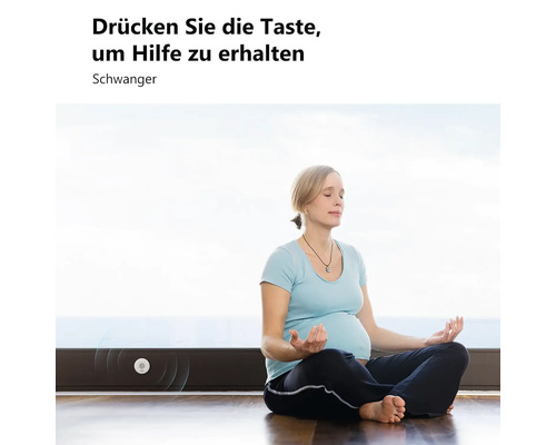 Eine schwangere Frau meditiert auf dem Boden neben einem an der Fußleiste montierten Notrufknopf mit dem Text Drücken Sie die Taste um Hilfe zu erhalten.
