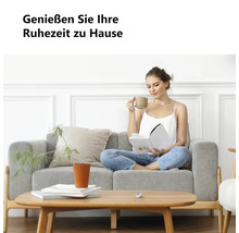"Eine Frau liest auf einem grauen Stoffsofa in einem hellen Wohnzimmer