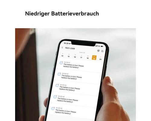 Main tenant un smartphone affichant des notifications de batterie faible pour un appareil de maison connectée.