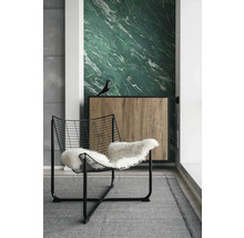 Pièce moderne avec papier peint marbre vert, fauteuil en fil de fer noir avec fourrure blanche et buffet en bois sur tapis gris.