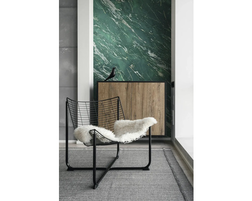 Pièce moderne avec papier peint marbre vert, fauteuil en fil de fer noir avec fourrure blanche et buffet en bois sur tapis gris.