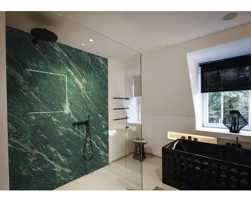 Salle de bains moderne avec panneau aspect marbre vert, robinetterie noire, paroi en verre et baignoire noire texturée.