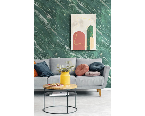Salon moderne avec papier peint effet marbre vert, canapé gris avec coussins décoratifs et table basse ronde devant une œuvre d'art abstraite.