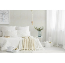 Chambre lumineuse et minimaliste avec lit blanc, jeté en tricot, suspension en corde, rideaux transparents et table en métal avec vase en verre.