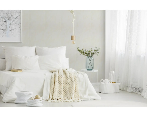Chambre lumineuse et minimaliste avec lit blanc, jeté en tricot, suspension en corde, rideaux transparents et table en métal avec vase en verre.