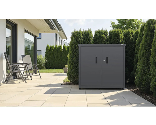 Armoire de jardin en métal anthracite avec doubles portes sur une terrasse à côté d une haie et de chaises de jardin.