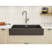 Évier de cuisine rustique sombre avec mitigeur à bec haut dans une cuisine lumineuse avec meubles en bois et plan de travail blanc.