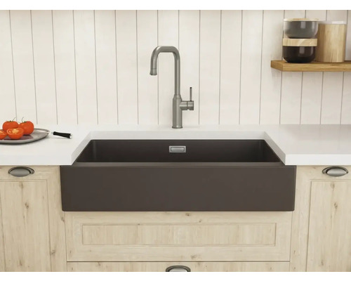 Dunkle Landhaus-Küchenspüle mit hoher Einhand-Armatur in einer hellen Küche mit Holzunterschränken und weißer Arbeitsplatte.