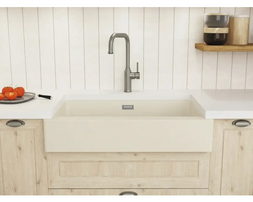 Helle Küche mit großem Keramik-Spülbecken, hoher Metallarmatur, Arbeitsplatte und Küchenschränken in Holzoptik.