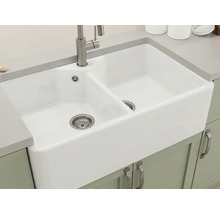 Weiße Doppel-Keramikspüle im Landhausstil mit Armatur aus gebürstetem Metall, eingebaut in eine graue Arbeitsplatte.