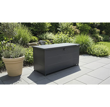 Biohort Gartenbox aus Metall in Anthrazit auf einer gepflasterten Terrasse in einem hellen Garten.