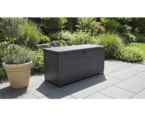Biohort Gartenbox aus Metall in Anthrazit auf einer gepflasterten Terrasse in einem hellen Garten.