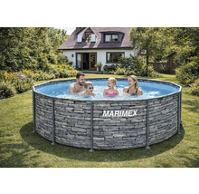 Famille dans une piscine hors sol ronde Marimex avec aspect pierre dans un jardin lumineux avec maison à l'arrière-plan.