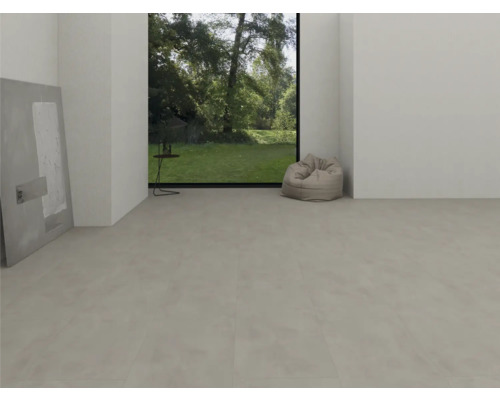 Pièce moderne et lumineuse avec sol en vinyle gris clair aspect béton, grande fenêtre donnant sur le jardin et un pouf.