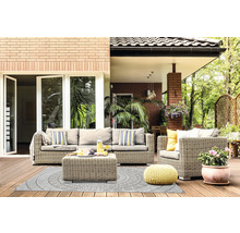 Terrasse lumineuse avec salon de jardin en rotin gris, tapis d'extérieur à motifs circulaires, pouf jaune et plante en pot sur plancher en bois.