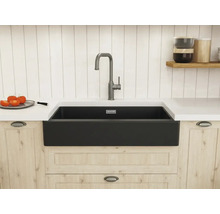 Moderne Küche mit schwarzer Schürzen-Spüle und hoher Armatur, eingebaut in helle Holzschränke mit weißer Arbeitsplatte.