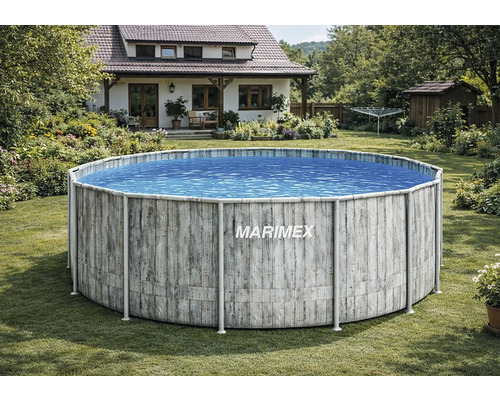 Une piscine hors sol ronde Marimex avec un décor en bois gris dans un jardin verdoyant devant une maison individuelle.