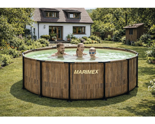 Runder Marimex Aufstellpool in Holzoptik in einem hellen, weitläufigen Garten mit einer Familie und einem Wohnhaus im Hintergrund.