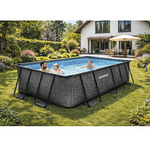 Sonnige Gartenanlage mit rechteckigem Marimex Frame Pool in Rattan-Optik, einer spielenden Familie im Wasser und einem Haus im Hintergrund.