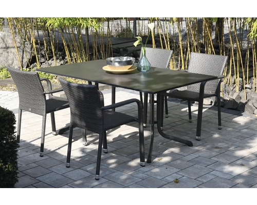 Ensemble de jardin avec une table rectangulaire et quatre chaises en rotin synthétique sur une terrasse pavée devant des bambous.