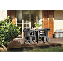 Set de mobilier de jardin en plastique avec table ovale et fauteuils sur une terrasse en bois ensoleillée devant la maison.